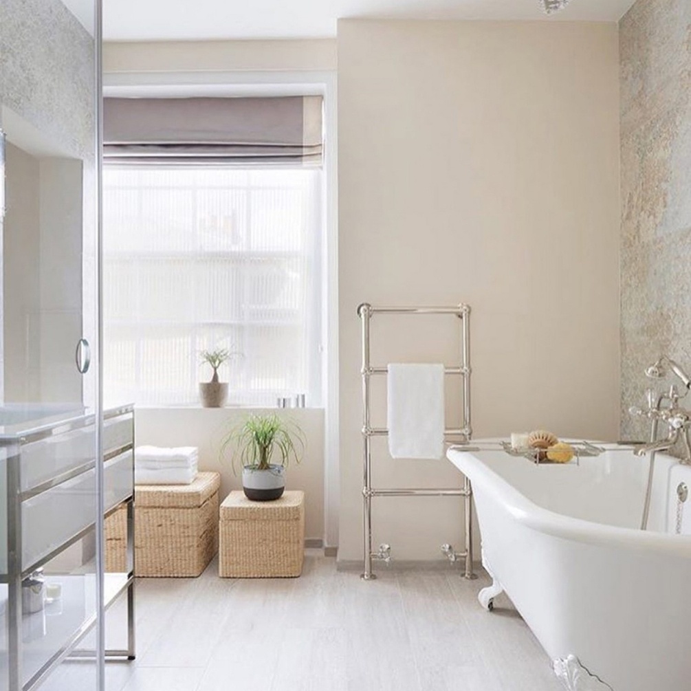 Lifestyle image of The Sussex Range by JIS Fletching 1200mm x 520mm Polished Stainless Steel Heated Floorstanding Towel Rail installed in a bathroom with double-ended bathtub